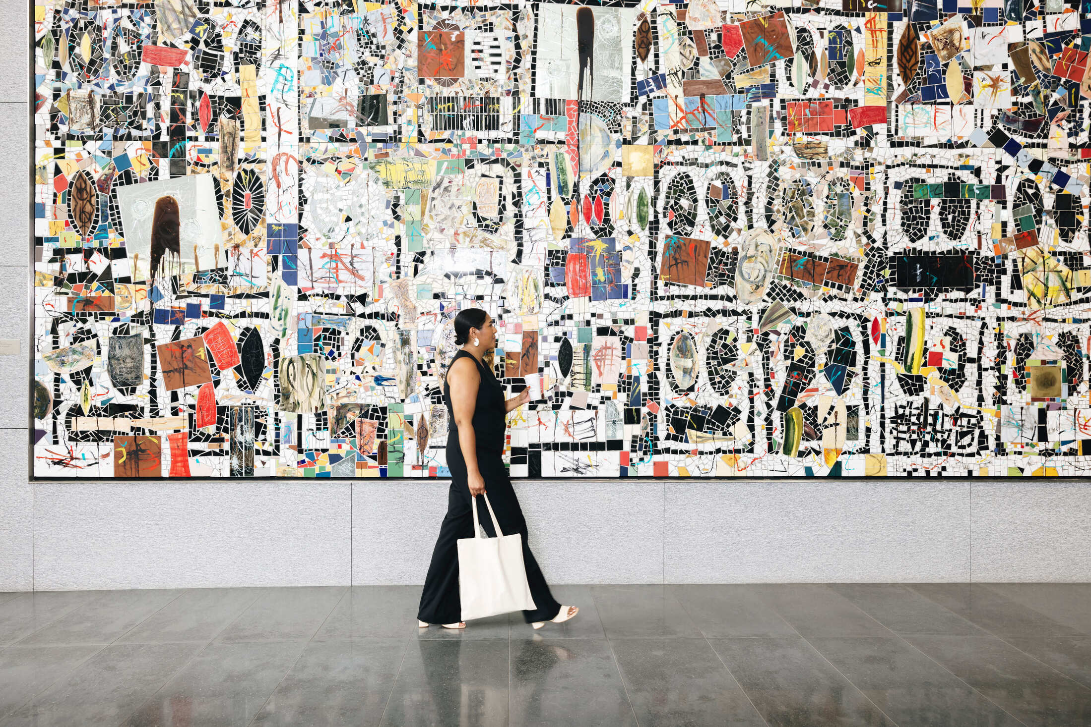 Overhead view of a person reaching out to touch a piece of patterned artwork or fabric.