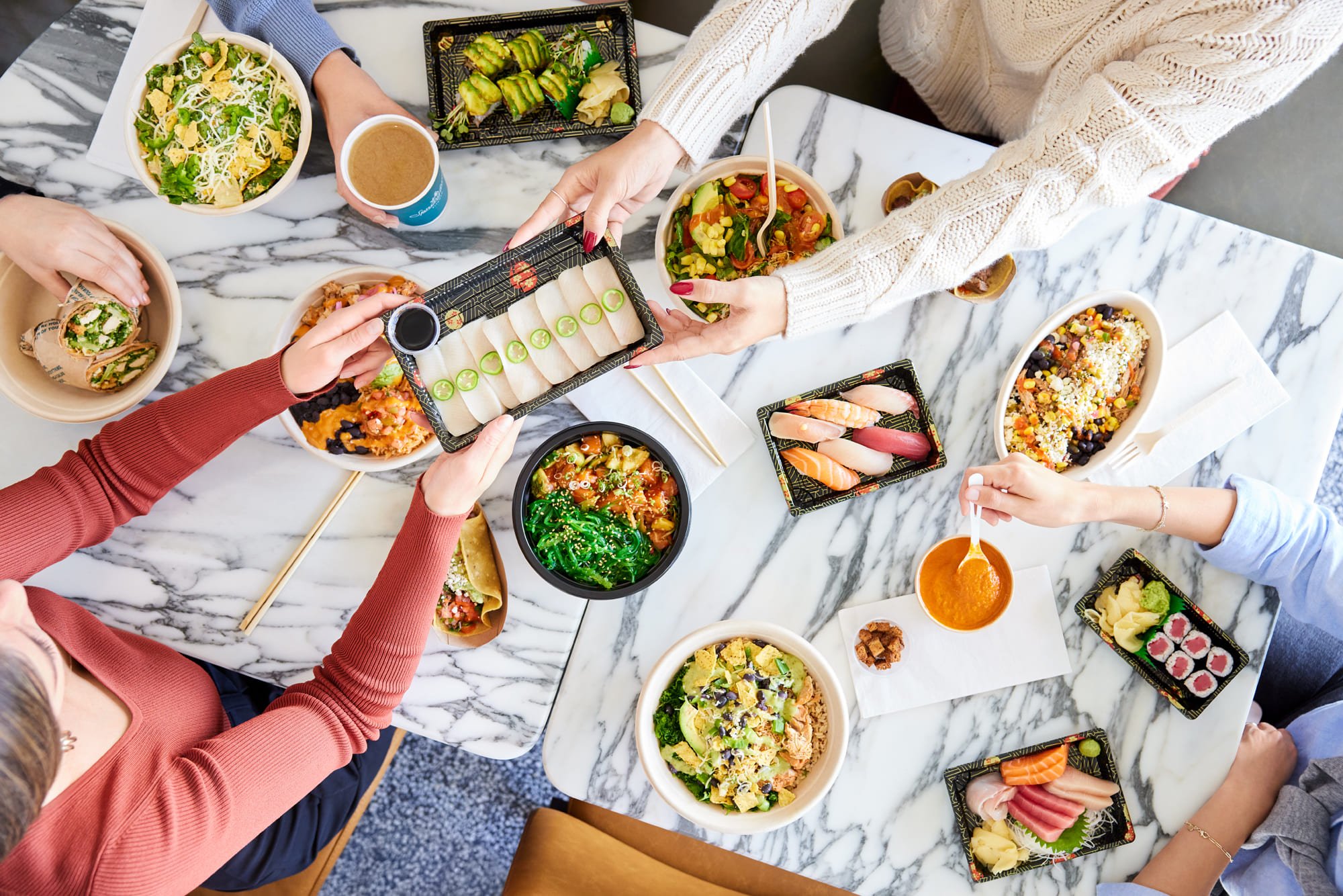 Overhead view of a table filled with various colorful dishes and food, typical of a shared meal.