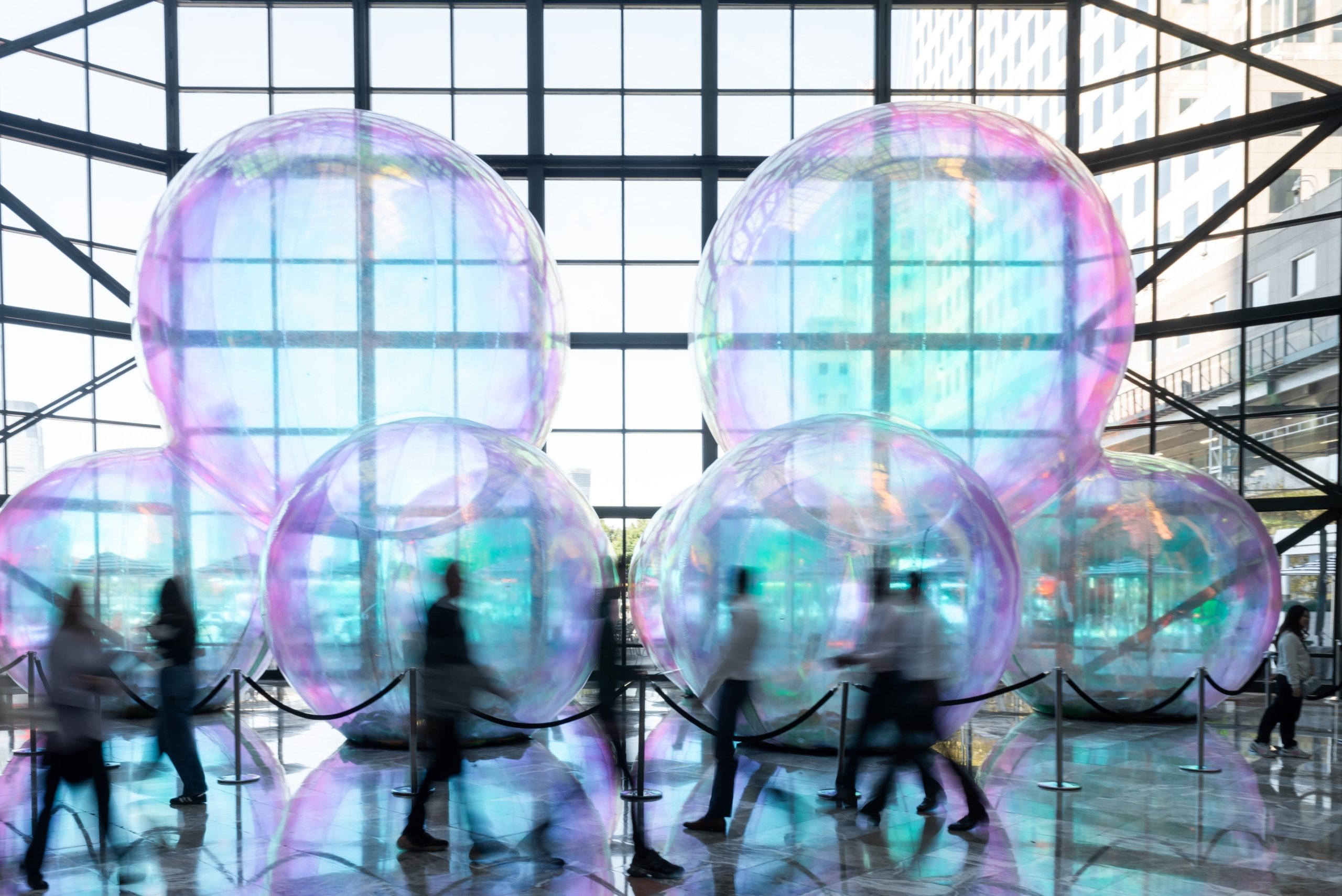 Group of people walking in front of giant bubbles art sculpture