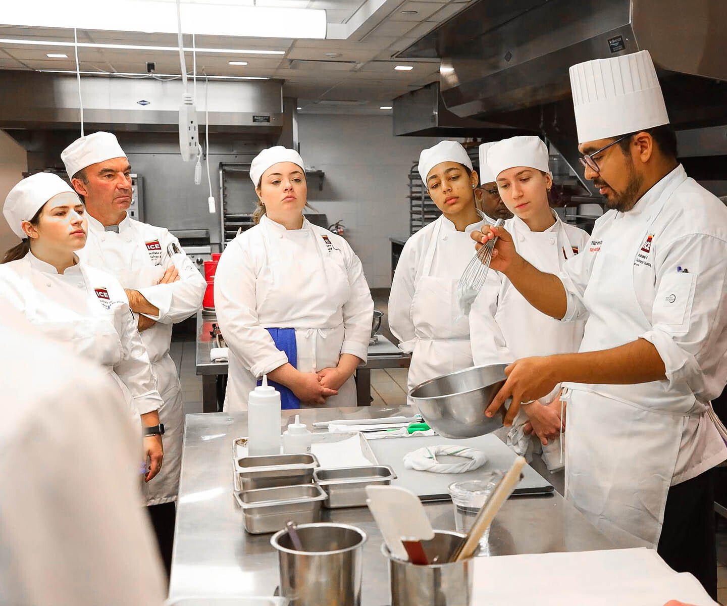 Group of chefs in white uniforms working together in a professional kitchen.
