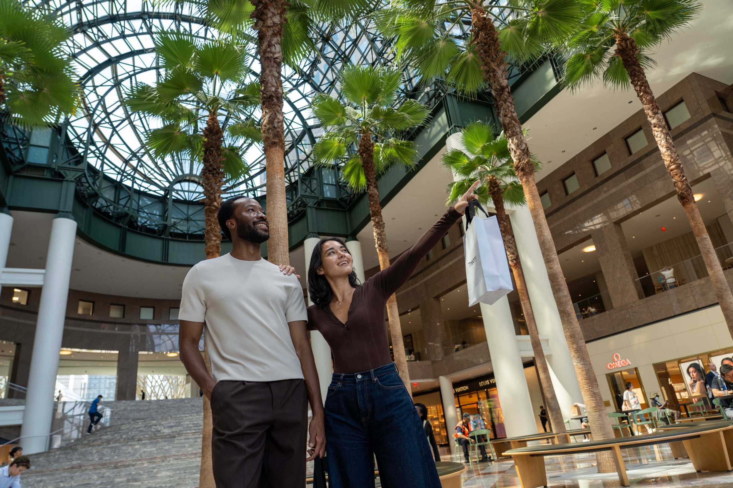 Two people looking at merchandise inside a brightly lit retail or hotel lobby space.