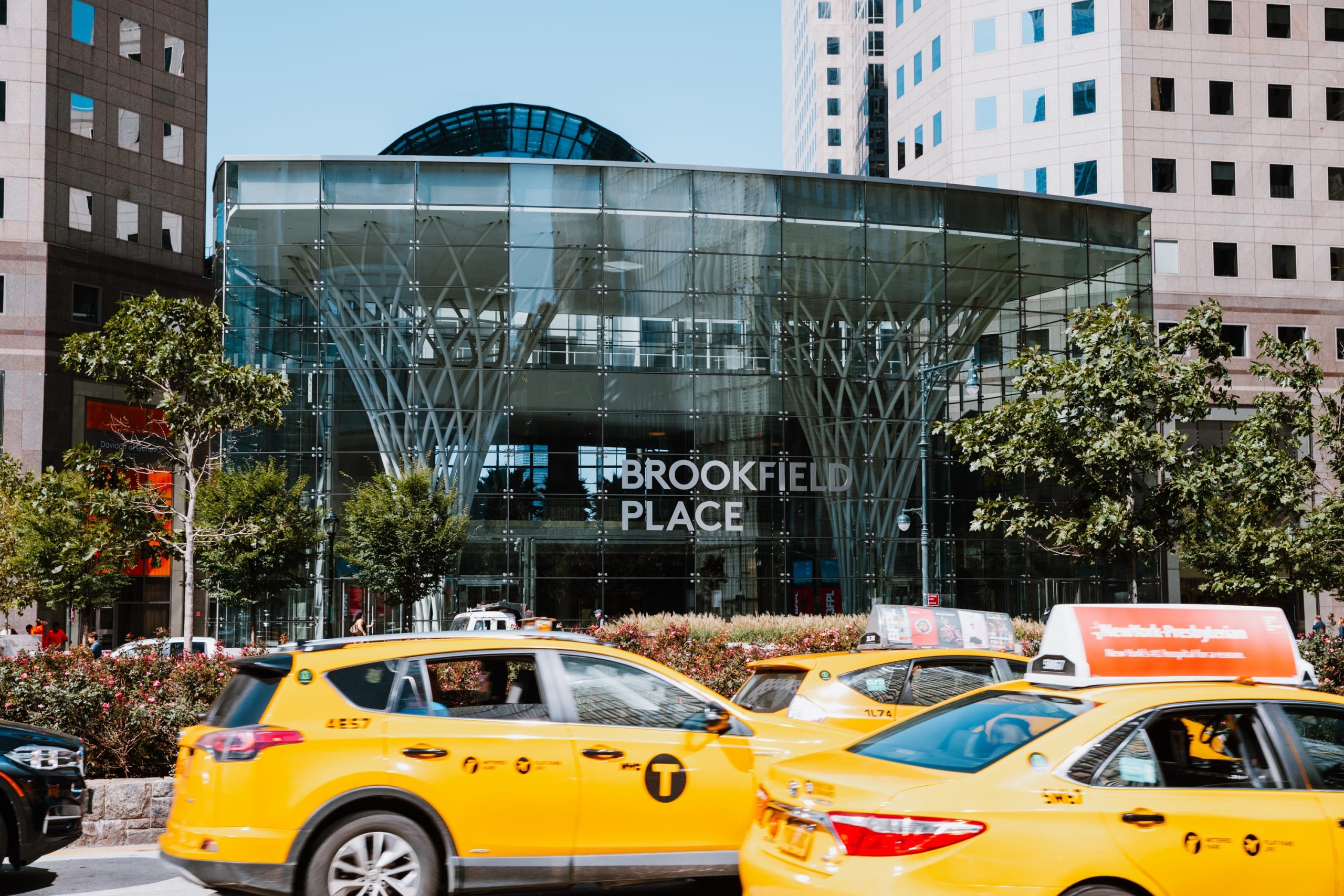View of Brookfield Place exterior with yellow taxis parked in front on a busy city street.