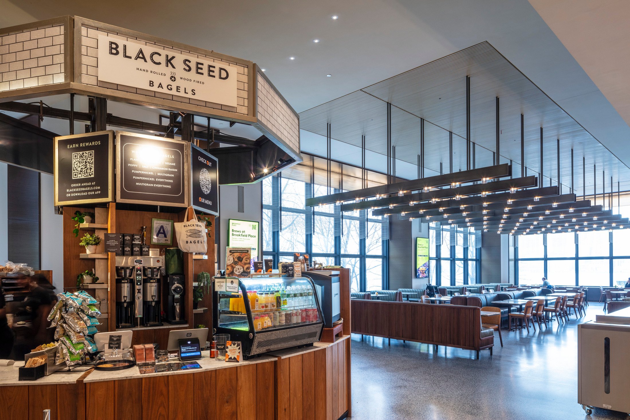 Interior view of Black Seed Bagel Bar with high ceilings, dark displays, and exposed ductwork.
