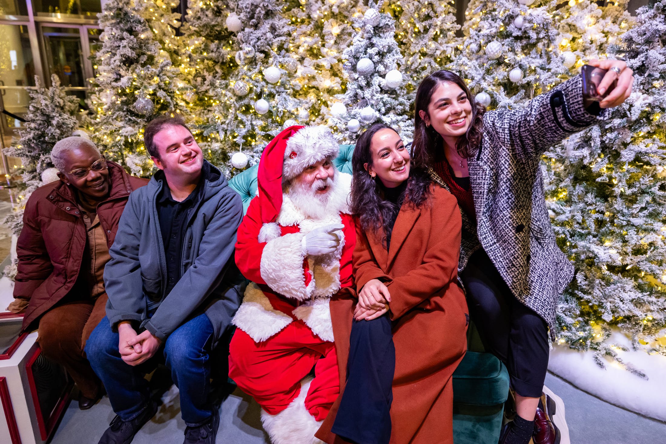Group of young adults posing for a cheerful holiday photo, with one person dressed as Santa Claus