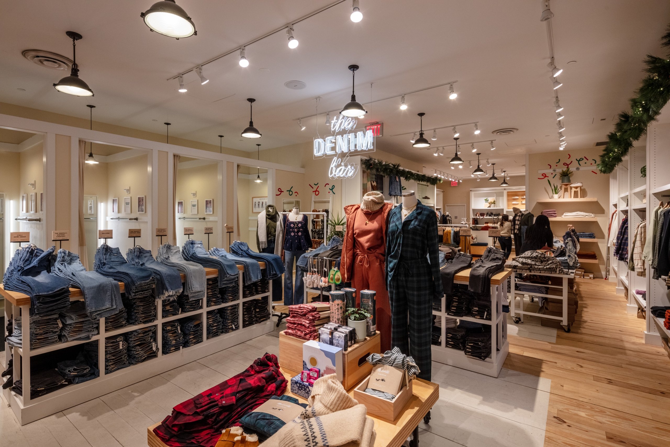 Bright retail store interior with clothing racks, mannequins, and wooden floors.