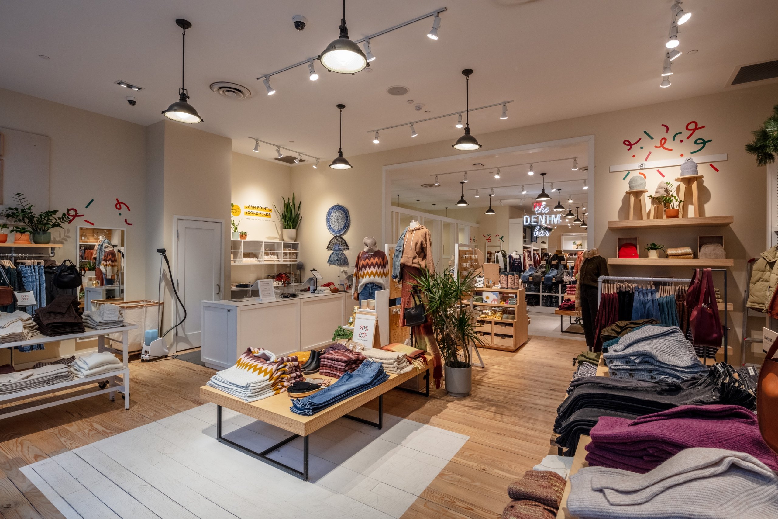 Upscale boutique or retail store interior with high ceilings, soft lighting, and diverse merchandise displays.
