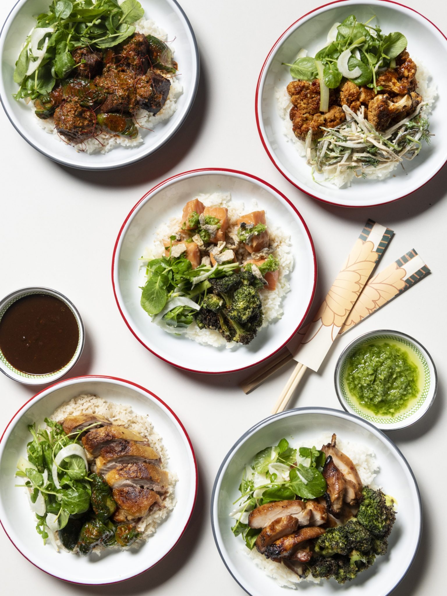 Overhead view of various small plates of food, featuring salads, grains, and dips.