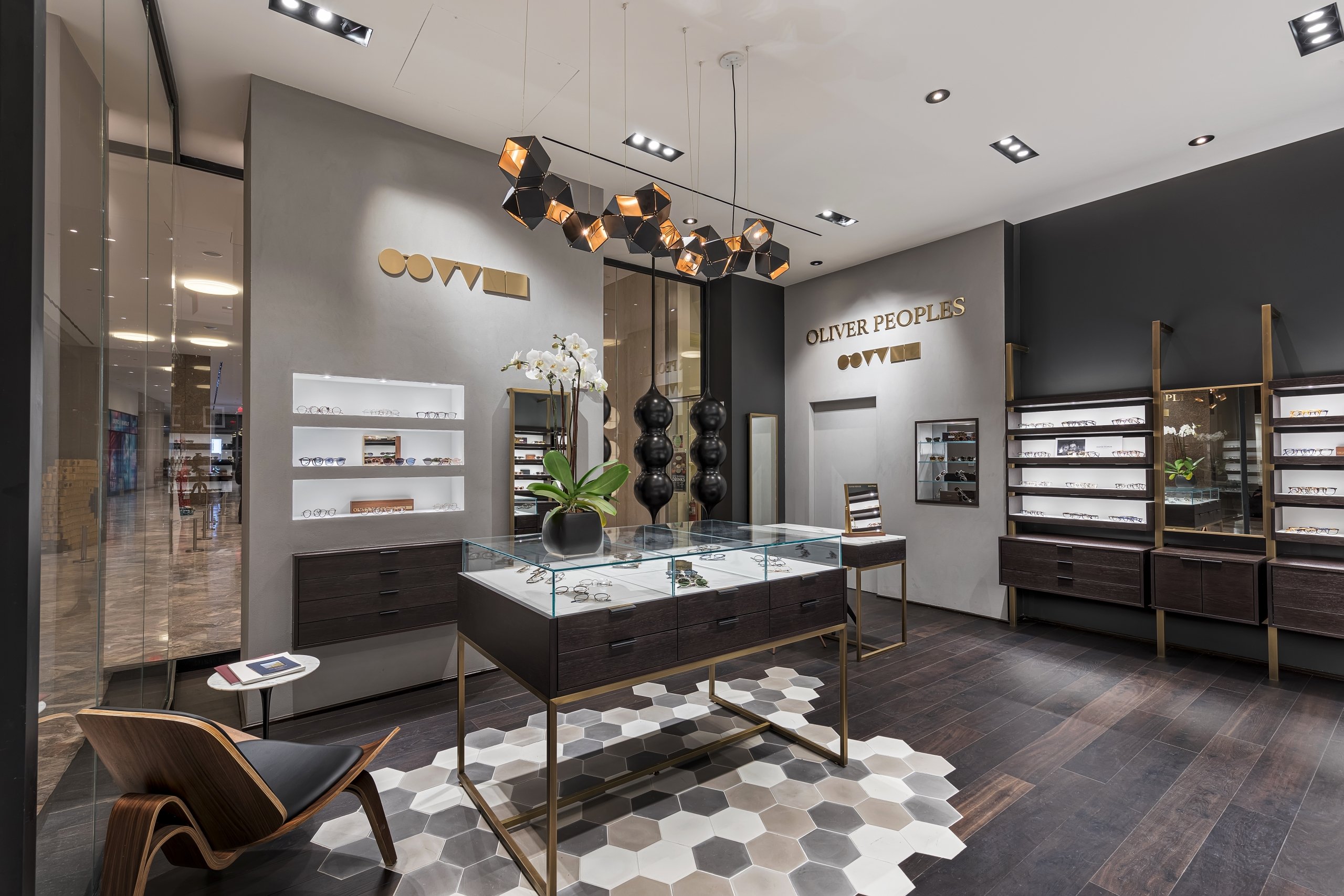 Oliver Peoples glasses store or showroom interior with dark wood displays and sleek furniture.