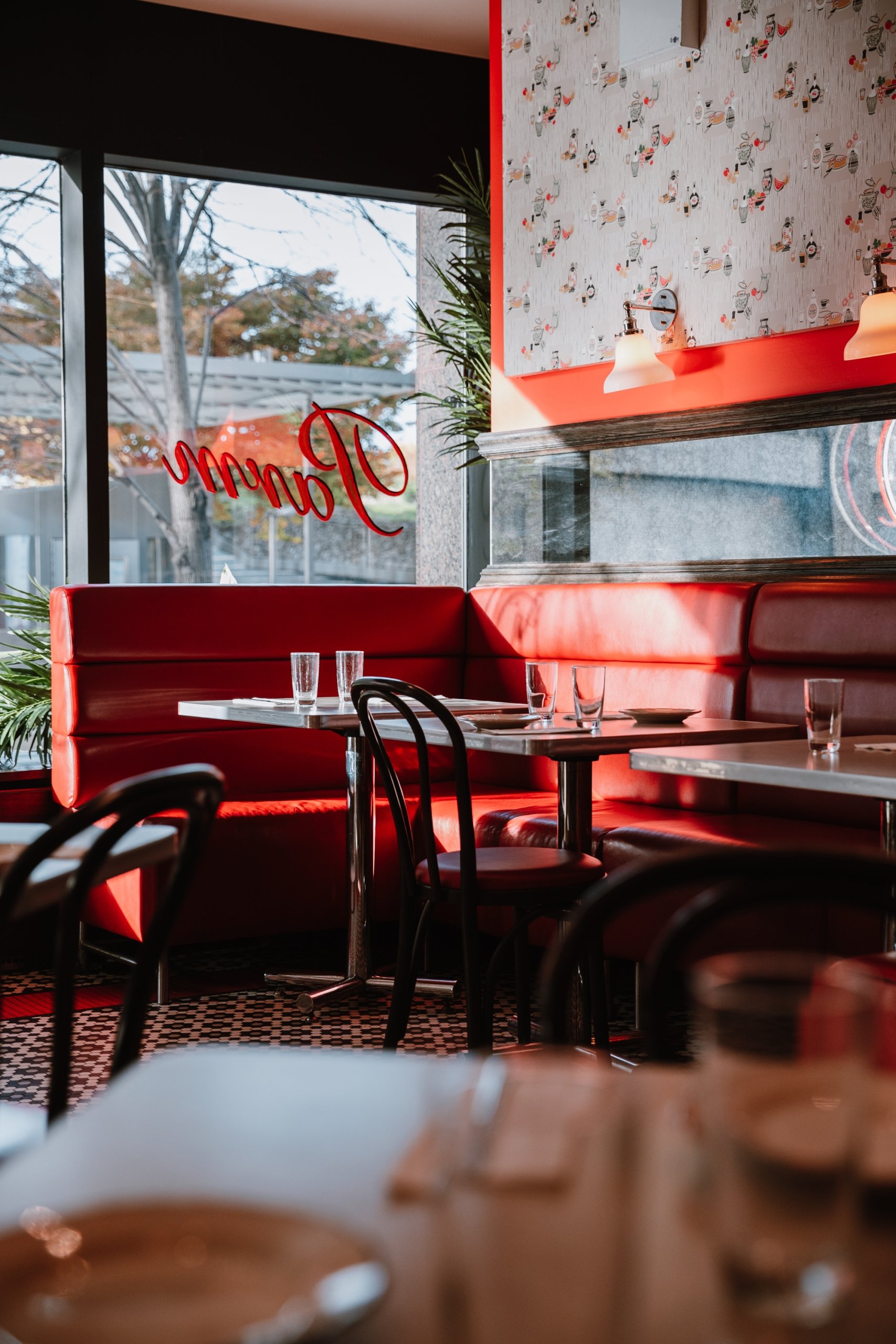 Restaurant interior of Parm with red leather booths, checkered floor, and warm lighting.