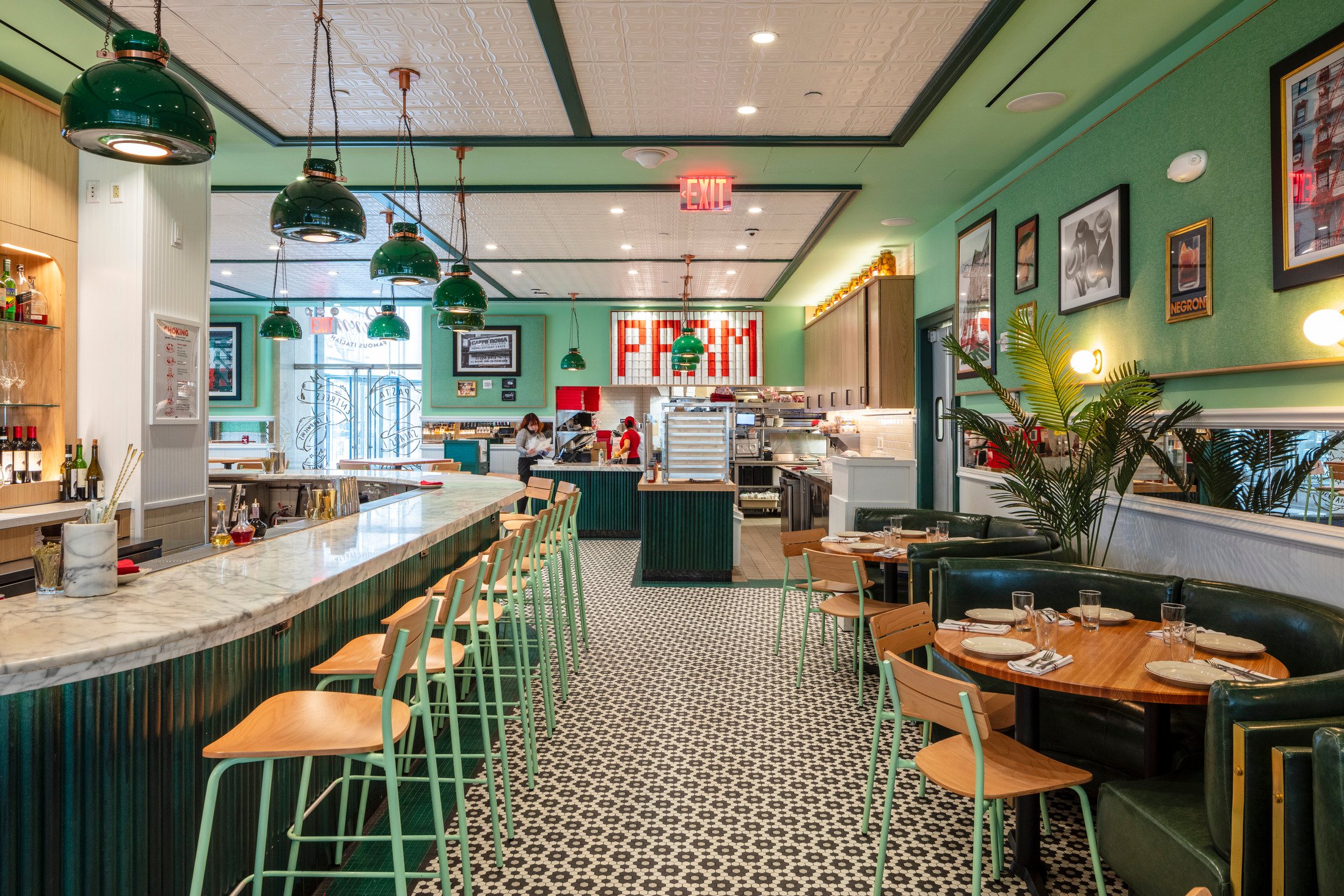 Bright, vintage-style café or restaurant interior with green walls, checkered floor, and a service counter.