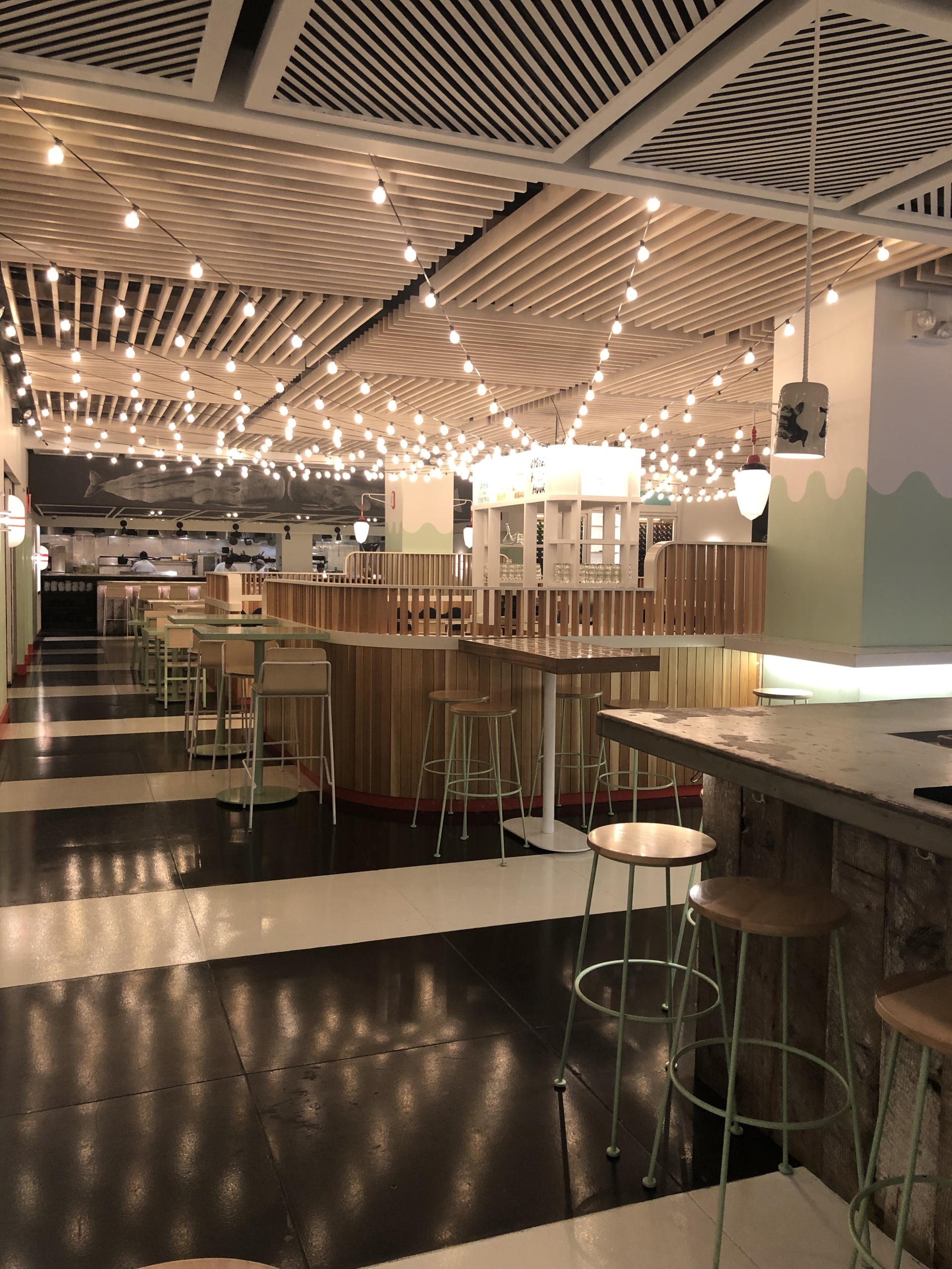 Wide shot of an upscale restaurant interior with leather banquettes and contemporary lighting fixtures.