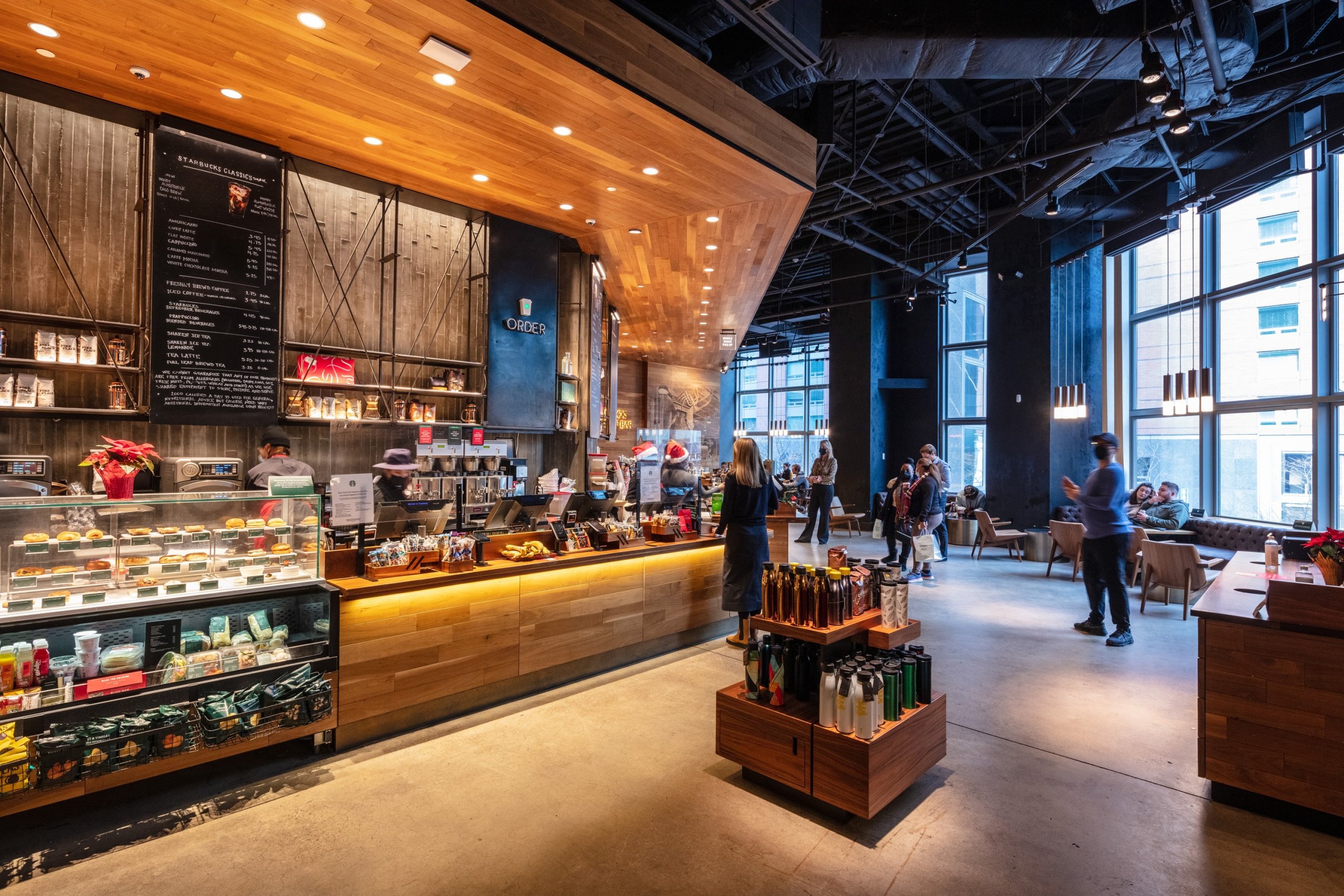 Modern Starbucks with exposed brick, wooden beams, and a view into a kitchen area.