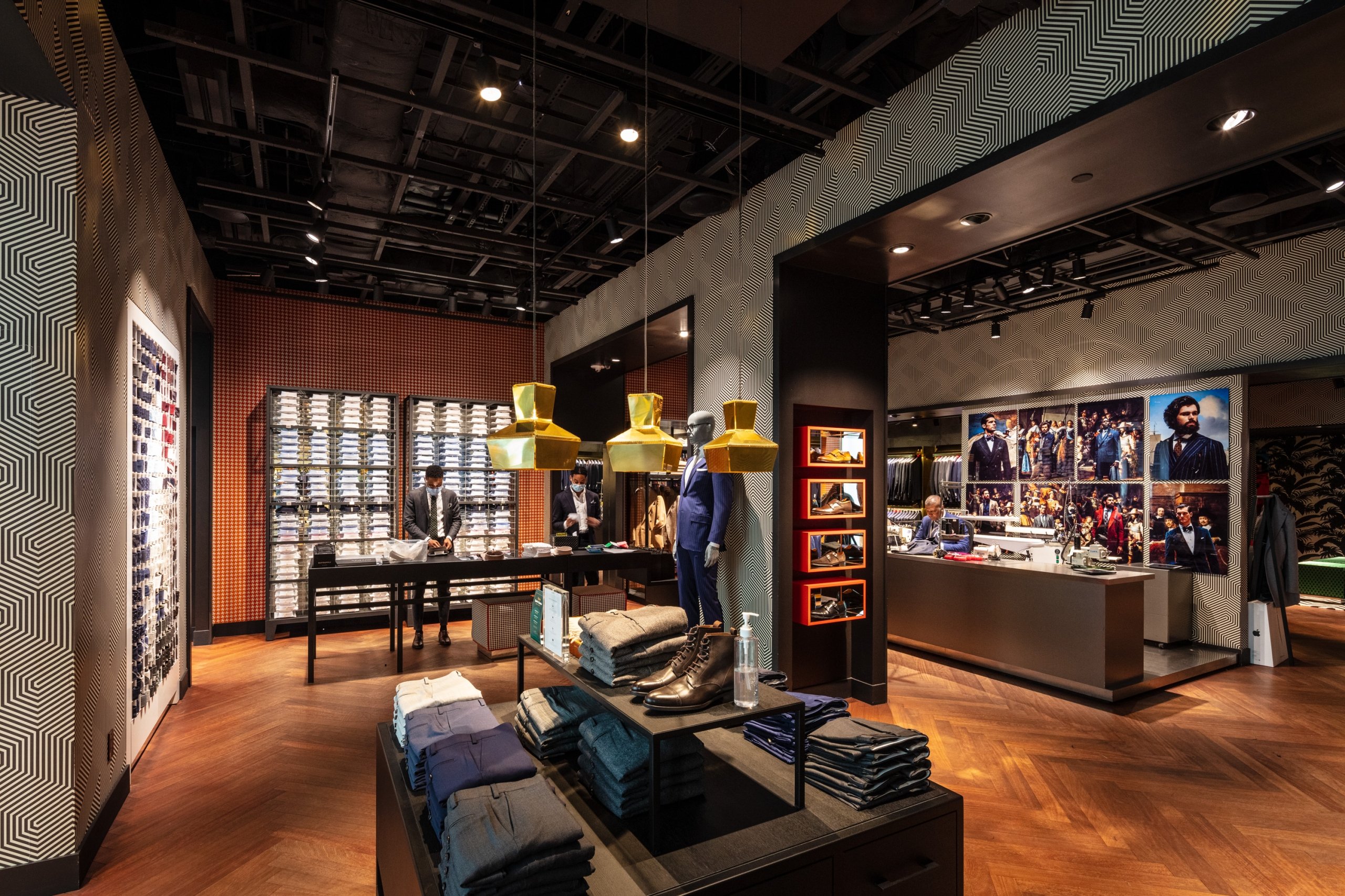 Cozy interior of Suit Supply with dark wood, comfortable armchairs, and warm lighting.