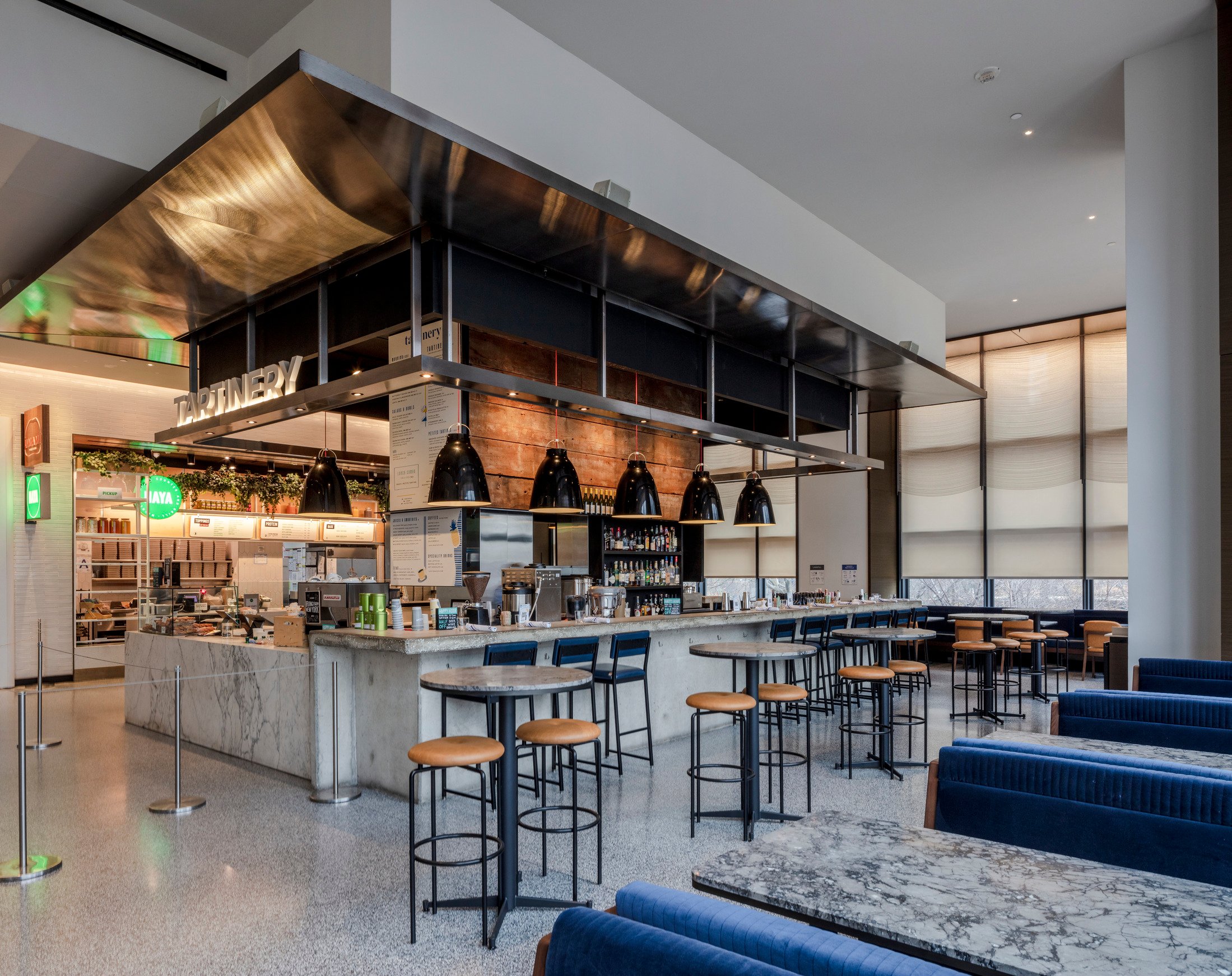 Interior view of a food court or restaurant with modern industrial design and metal bar seating.