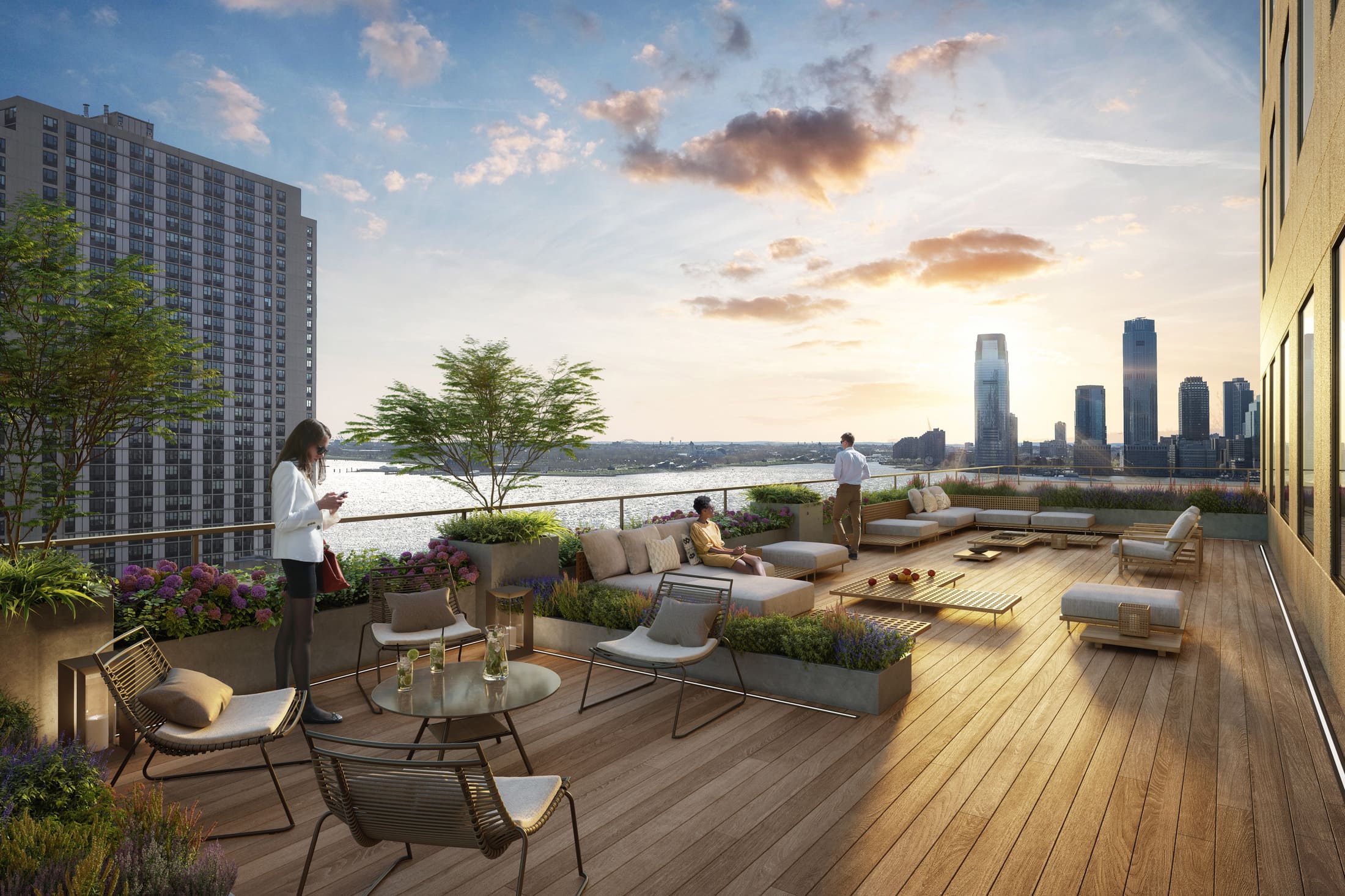 Outdoor rooftop patio or terrace with wooden flooring, casual seating, and views of a waterfront and sunset.